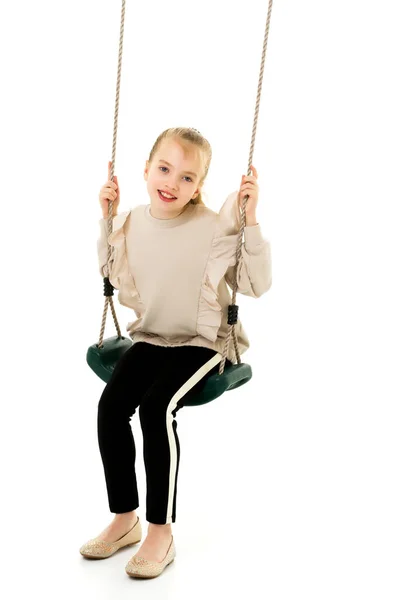 Gelukkig klein meisje schoolmeisje swinging op een swing. — Stockfoto