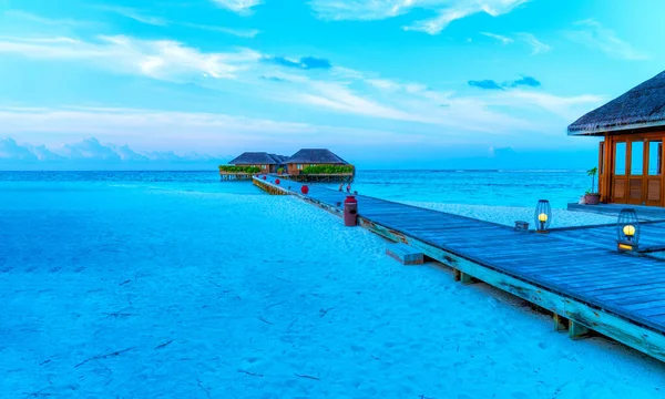 Houten bruggen die leiden naar de hutten aan de kust van de tropische, warme zee. Malediven. Toerisme. — Stockfoto