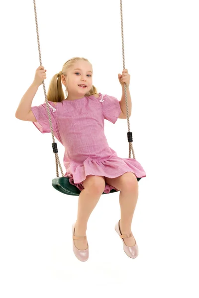 Lycklig liten flicka skolflicka svänger på en gunga. — Stockfoto