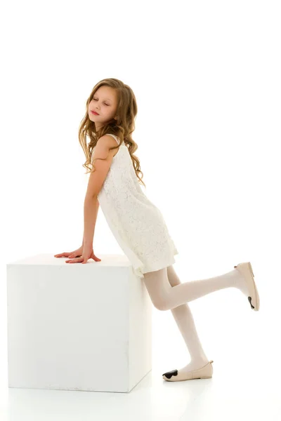 美しいです女の子でホワイトドレス立ちとleaning上のキューブ. — ストック写真