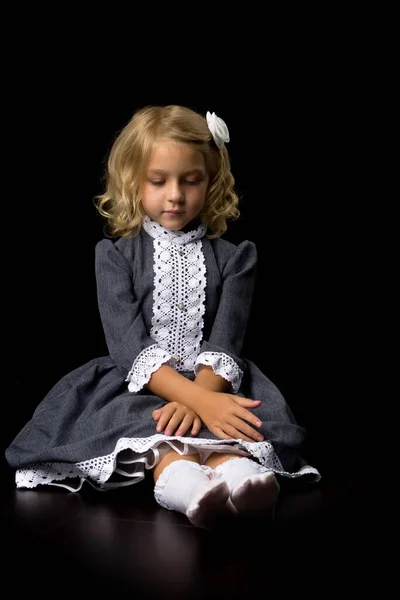 Menina está sentada no chão.O conceito de uma criança feliz.Isolado sobre fundo preto. — Fotografia de Stock