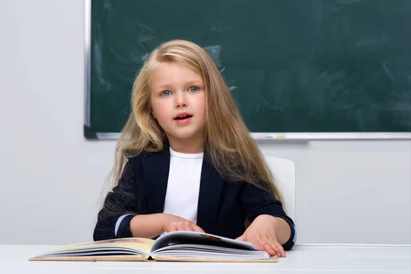 Gelukkig schoolmeisje zit aan het bureau — Stockfoto