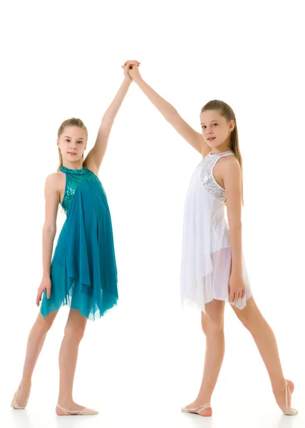 Dos hermanas en vestidos deportivos bailando en estudio sobre fondo blanco. — Foto de Stock