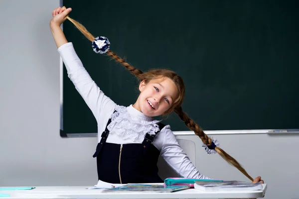 Skolflicka håller i flätorna. Tillbaka till skolan, utbildningskoncept. — Stockfoto