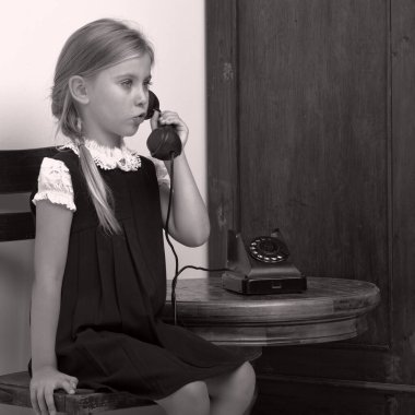 Şirin bir kız, eski bir fonla konuşuyor.