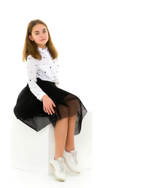Портрет милої дівчини, що сидить на білому кубі руки на колінах — стокове фото