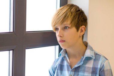 Pencereden dışarı bakan genç bir çocuk.