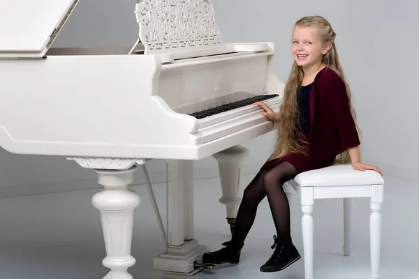 Smiling girl playing grand piano