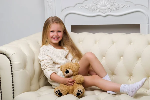 女孩坐在沙发上抱着泰迪熊 — 图库照片