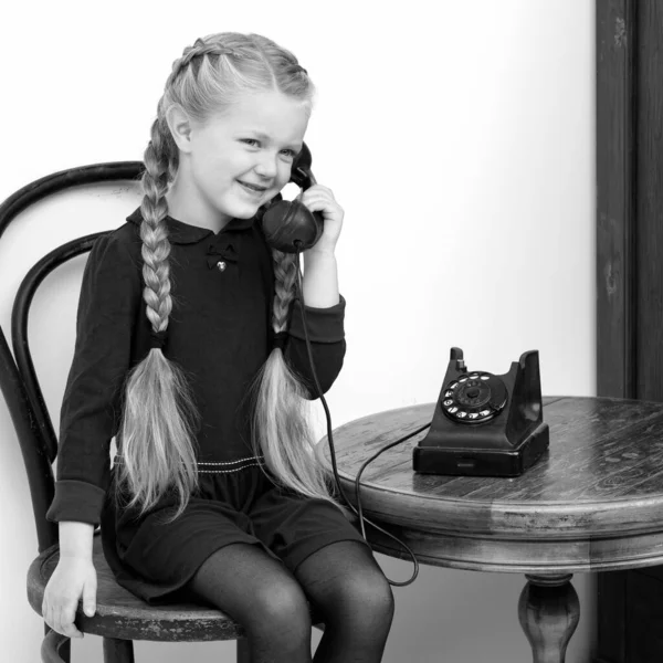En leende flicka som pratar med gamla telefoner. Studioporträtt. — Stockfoto