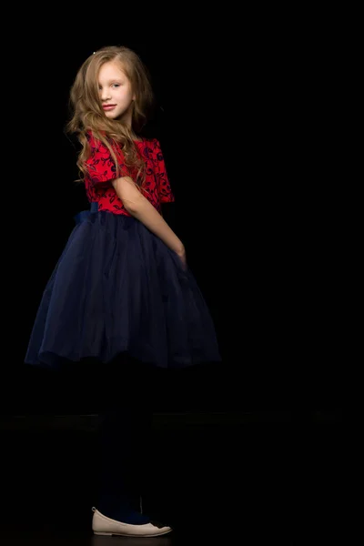 Schöne Mädchen in einem Tutu-Kleid posiert im Studio auf einem schwarzen B — Stockfoto