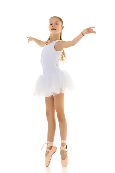 Schattig klein meisje in een tutu en pointe schoenen dansen in de studio op een witte achtergrond. — Stockfoto