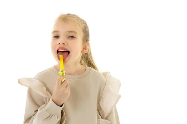 La ragazzina carina lecca una caramella. Concetto di infanzia felice — Foto Stock