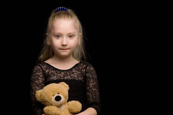 Kleines Mädchen mit einem Teddybär auf schwarzem Hintergrund. — Stockfoto