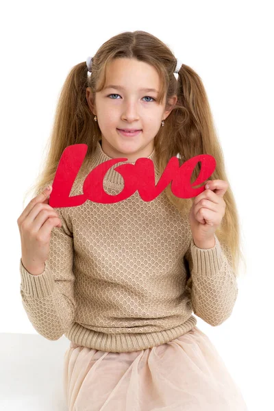 Preadolescente chica sosteniendo rojo palabra amor —  Fotos de Stock