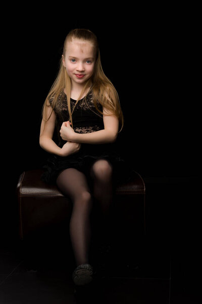 A beautiful little girl straightens her hair on her head.