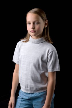 Siyah arka planda poz veren sevimli, gülümseyen küçük bir kızın yakın görüntüsü.