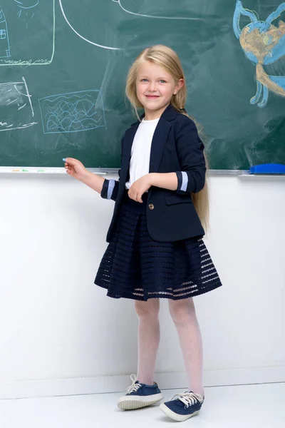 Belle écolière debout au tableau noir — Photo