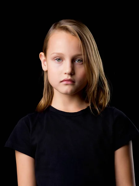 Retrato de cerca de una hermosa adolescente rubia con una camiseta negra sobre un fondo negro. — Foto de Stock