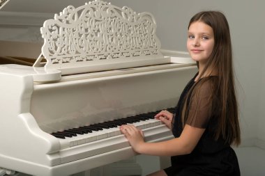 Beyaz kuyruklu piyanoda poz veren genç kız