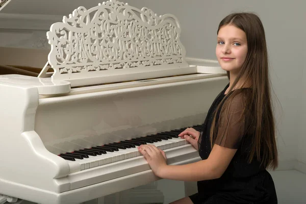 Beyaz kuyruklu piyanoda poz veren genç kız