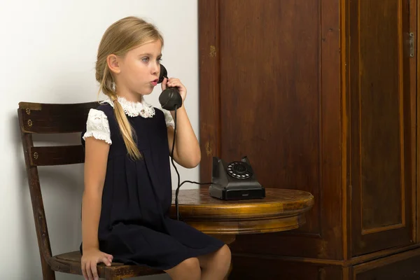 Милая девушка говорит по старинному телефону — стоковое фото