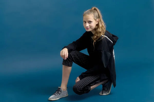 Menina adolescente com capuz preto sentado no chão — Fotografia de Stock