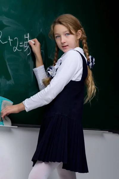 Schülerin schreibt auf Kreidetafel im Klassenzimmer — Stockfoto