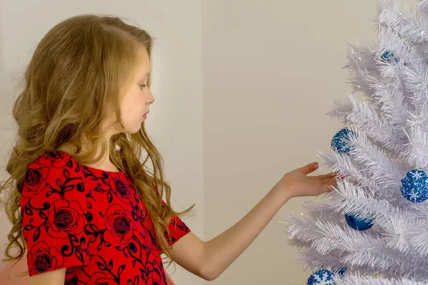 Vista lateral de hermosa chica posando Siguiente árbol de Navidad blanco — Foto de Stock