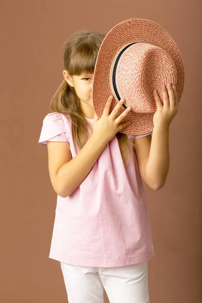 Meisje bedekt haar gezicht met een strohoed — Stockfoto