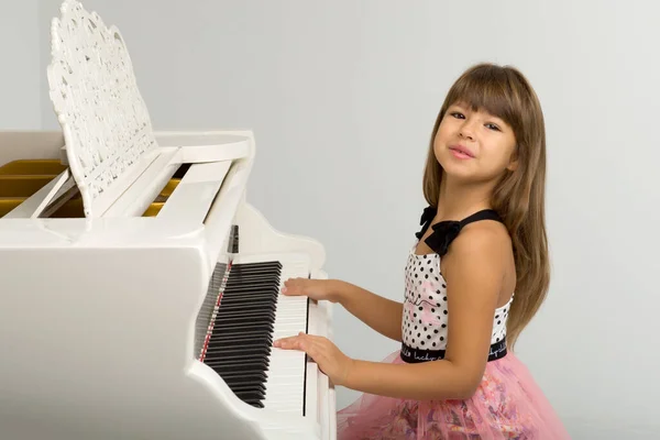 年轻姑娘在白色的大钢琴前摆姿势 — 图库照片