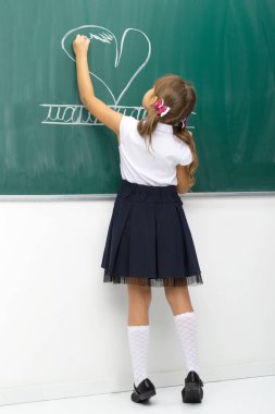 Tahtaya tebeşirle kalp çizen kız.