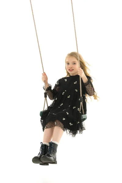 Feliz niña colegiala balanceándose en un columpio. — Foto de Stock