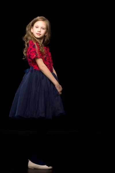 Schöne Mädchen in einem Tutu-Kleid posiert im Studio auf einem schwarzen B — Stockfoto