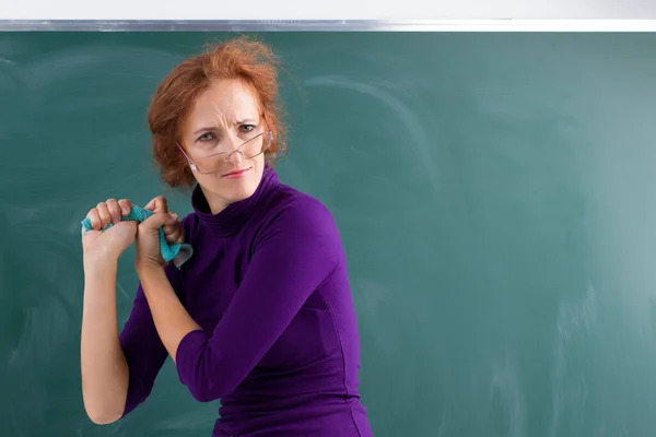 Angry teacher wringing out rag at blackboard
