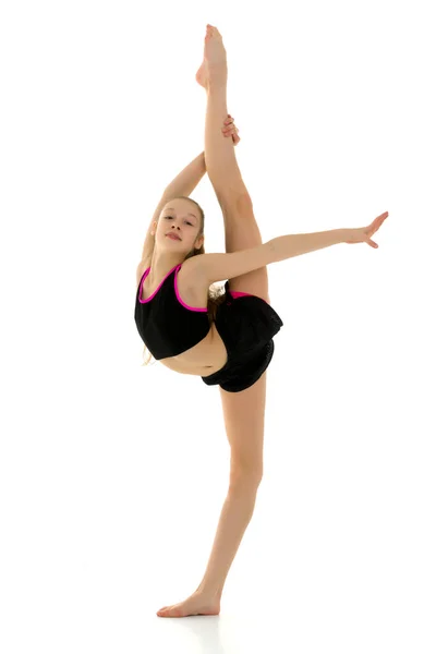 Chica gimnasta haciendo divisiones verticales sosteniendo su pierna con su mano —  Fotos de Stock