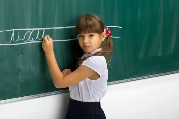 Серьёзная школьница, стоящая у доски — стоковое фото