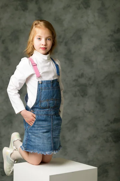 Klein meisje in een korte denim jurk. — Stockfoto