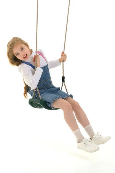 Gelukkig klein meisje schoolmeisje swinging op een swing. — Stockfoto