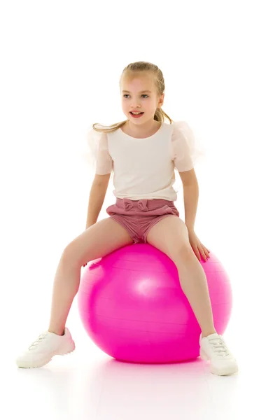 Liten flicka leker med en stor boll för fitness — Stockfoto