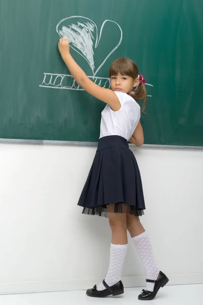 Flicka rita hjärta med krita på svarta tavlan — Stockfoto