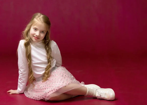 La niña está sentada en el suelo.El concepto de un niño feliz — Foto de Stock