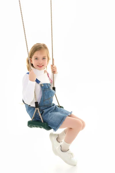 Gelukkig klein meisje schoolmeisje swinging op een swing. — Stockfoto