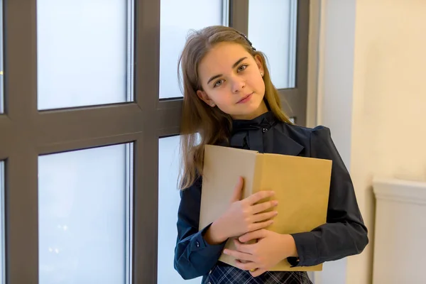 Söt liten flicka läser en bok vid fönstret. — Stockfoto