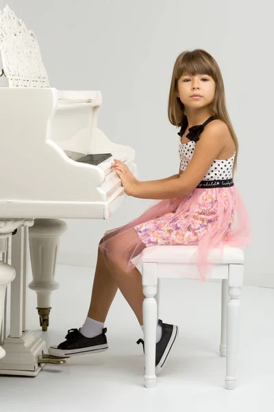 Menina posando no piano de cauda branco — Fotografia de Stock