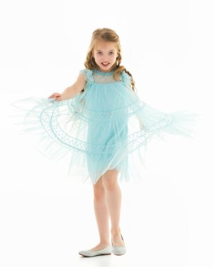 Küçük bir kız ellerini eteğin kenarlarında tutuyor..