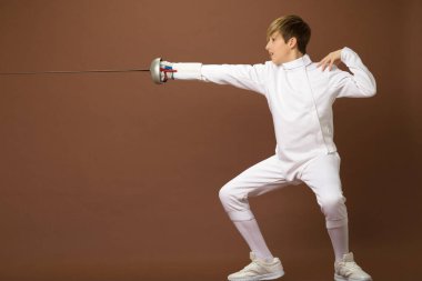 Çocuk eskrimci saldırı pozisyonunda duruyor.