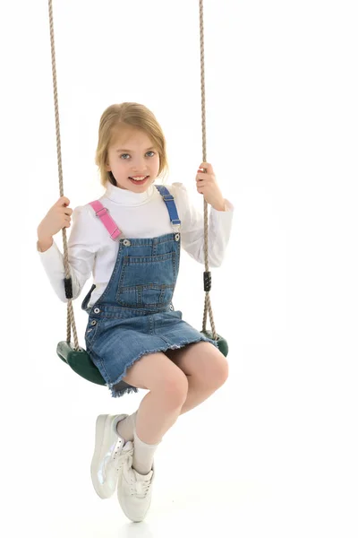Feliz niña colegiala balanceándose en un columpio. —  Fotos de Stock