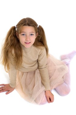 Mutlu küçük kız yerde oturuyor.