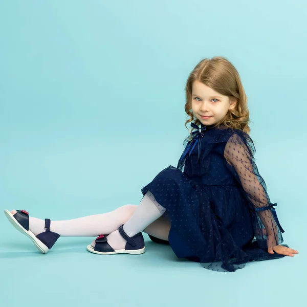 Menina feliz em vestido azul sentado no chão — Fotografia de Stock